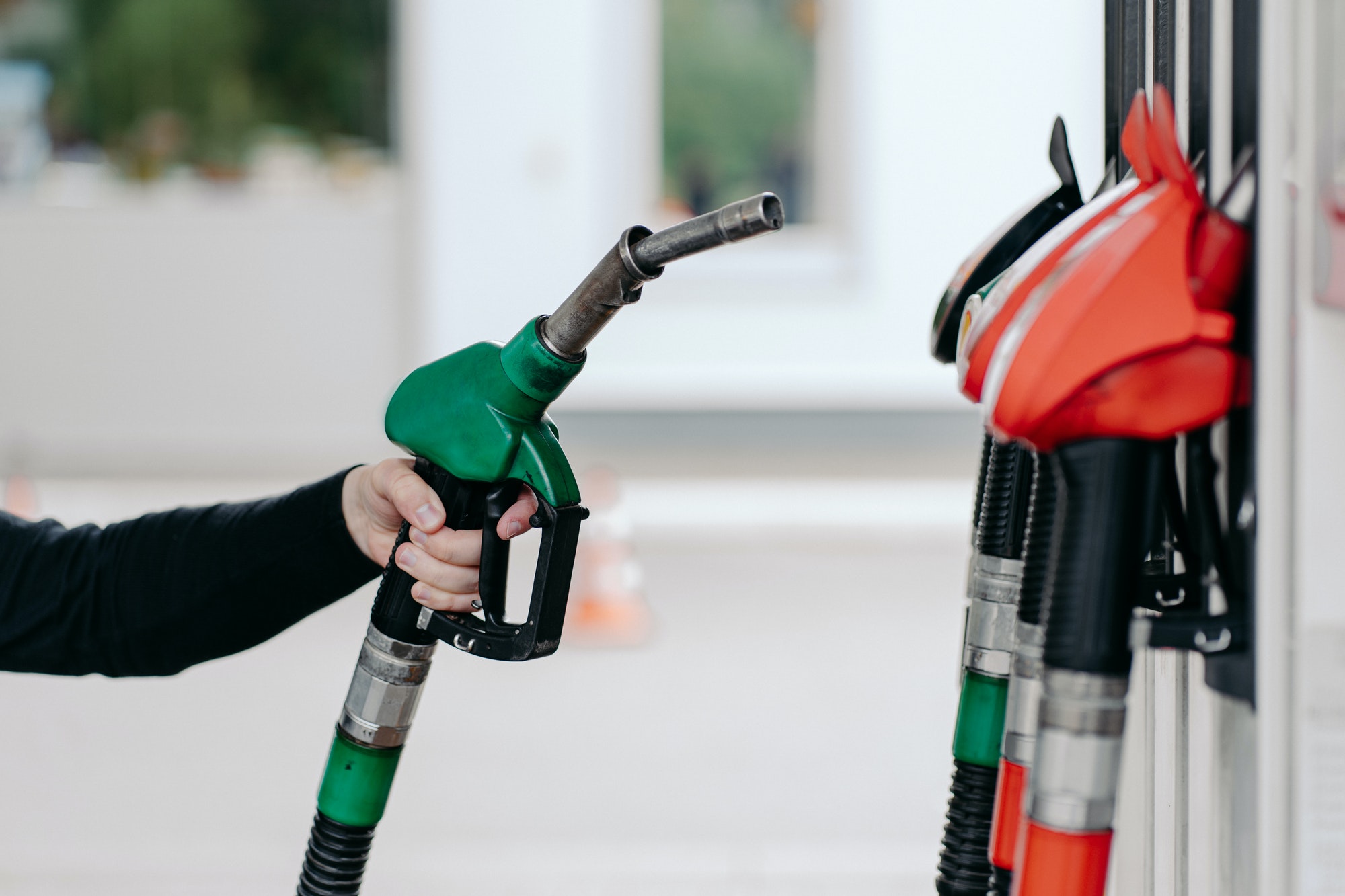 Car fuelling concept. Mans hand using fuel nozzle at petrol station. Refuelling pistols close up